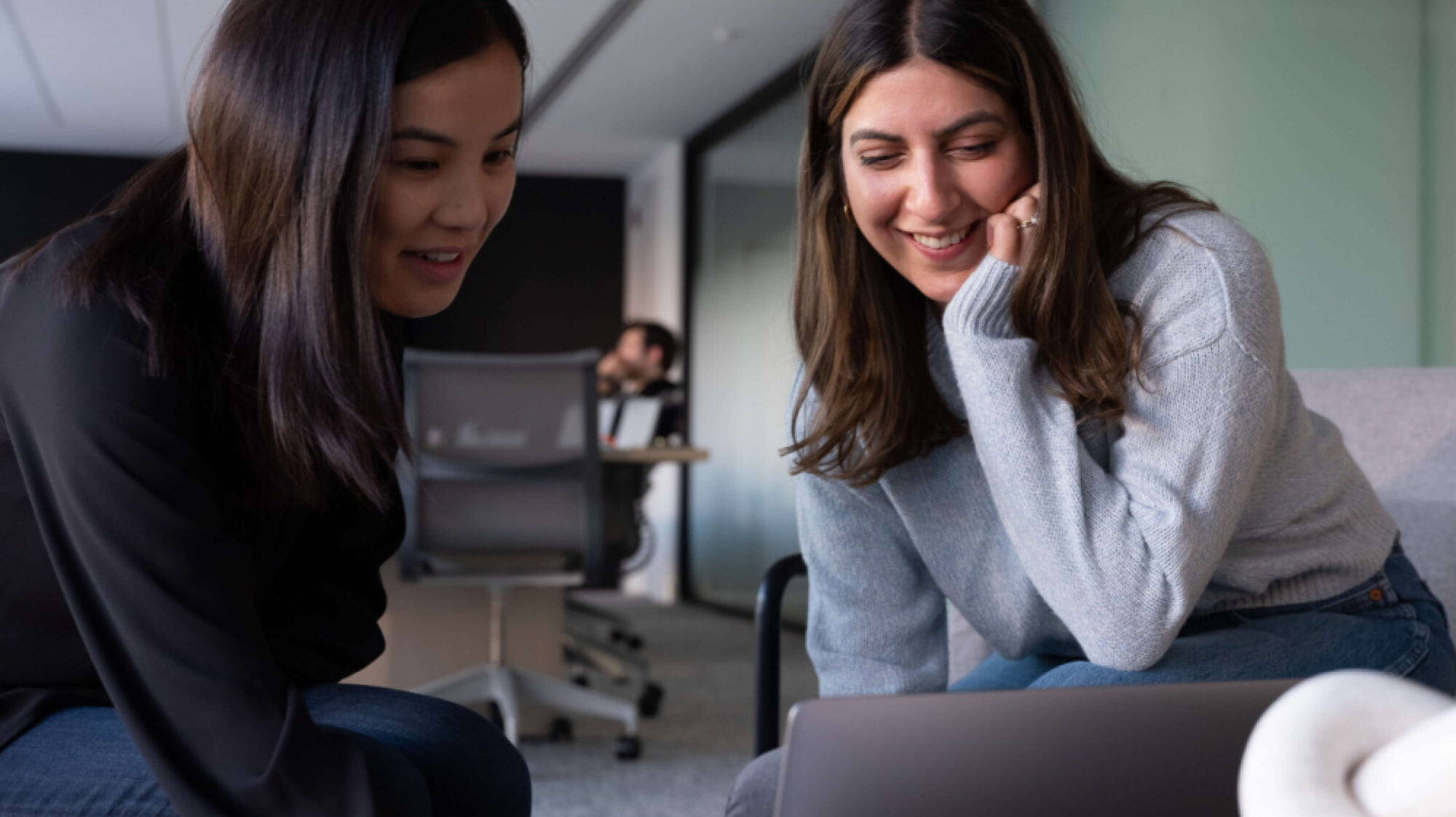 Two women in a conference room working on a laptop