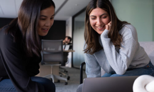 Two women in a conference room working on a laptop