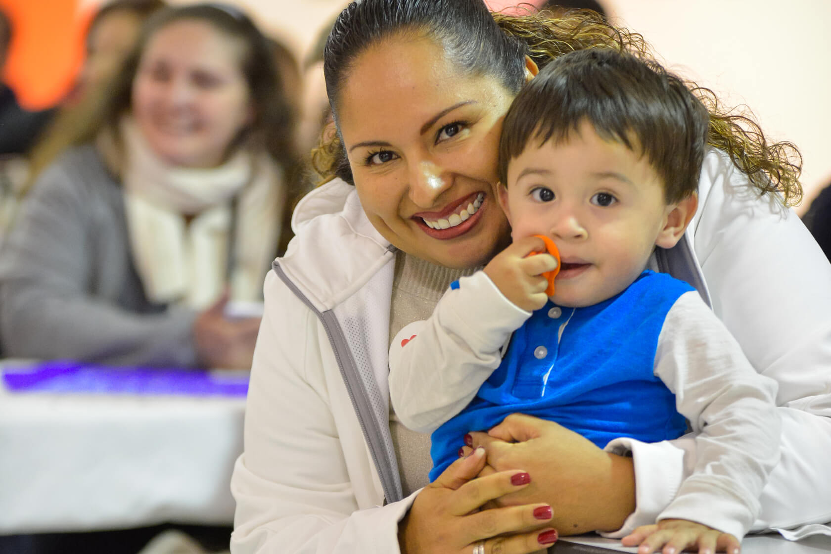 A woman and toddler smile at the camera