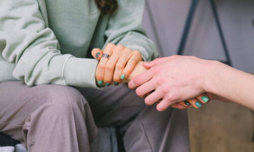 Two people holding hands during a therapy session.