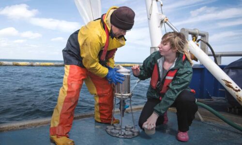 Man and woman working together on a ship in the middle of the sea.